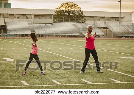 Grandmother and granddaughter exercising on football field View Large Photo Image Stock Photo - Grandmother and granddaughter exercising on football field. Fotosearch