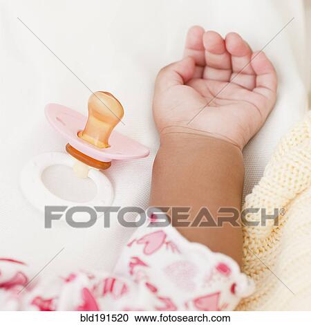 Stock Image - Hand of African baby and pacifier. Fotosearch
