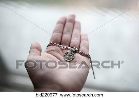 Stock Photo - Hand of Caucasian woman holding necklace. Fotosearch