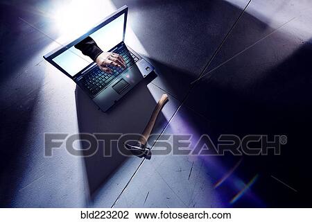 Stock Image - Hand of hacker reaching from screen of laptop and typing. Fotosearch
