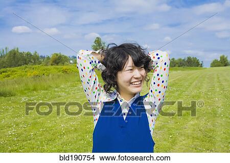 Happy Asian woman standing in park View Large Photo Image Picture - Happy Asian woman standing in park. Fotosearch