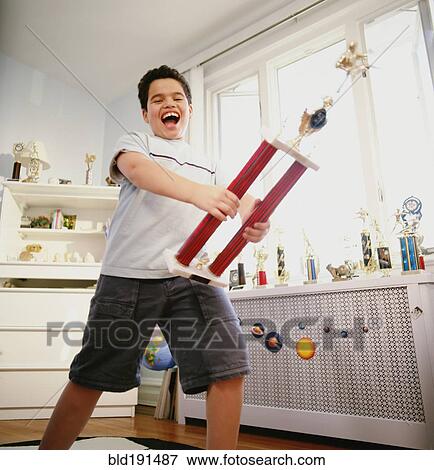 Happy Hispanic boy holding trophy in bedroom View Large Photo Image Stock Photo - Happy Hispanic boy holding trophy in bedroom. Fotosearch