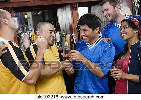 Stock Photography - Happy men shaking hands in sports bar. Fotosearch