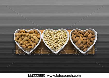 Stock Image - Heart-shaped bowls of heart-healthy nuts. Fotosearch