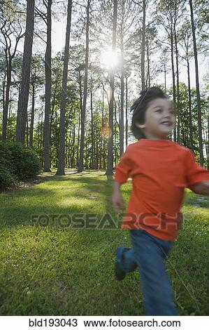 Stock Image - Hispanic boy running in forest. Fotosearch