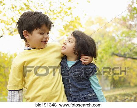 Stock Photo - Hispanic brother and sister hugging outdoors in autumn. Fotosearch