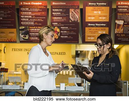 Stock Photography - Hispanic business owner talking to employee in cafe. Fotosearch