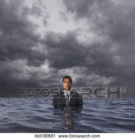 Stock Image - Hispanic businessman standing in water. Fotosearch