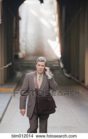 Picture - Hispanic businessman using cell phone on city street. Fotosearch