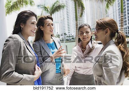 Stock Image - Hispanic businesswomen talking outdoors. Fotosearch