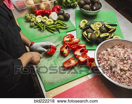 Stock Photo - Hispanic chef cutting vegetables in kitchen. Fotosearch