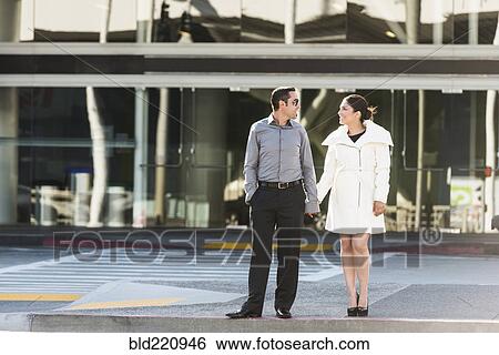 Hispanic couple holding hands on city sidewalk View Large Photo Image Stock Photograph - Hispanic couple holding hands on city sidewalk. Fotosearch