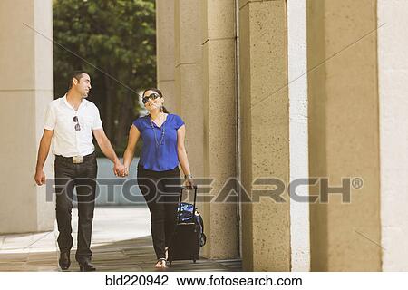 Stock Image - Hispanic couple holding hands under columns. Fotosearch