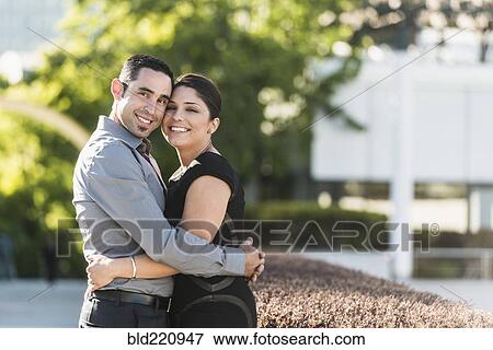 Stock Photo - Hispanic couple hugging in city. Fotosearch