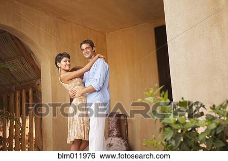 Stock Photograph - Hispanic couple hugging on front stoop. Fotosearch
