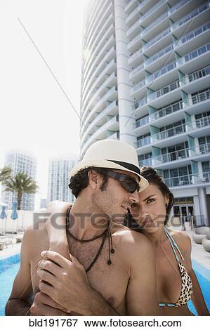 Stock Photo - Hispanic couple hugging poolside. Fotosearch