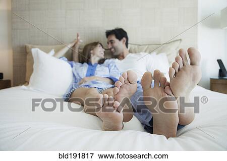 Stock Photo - Hispanic couple laying on bed with bare feet. Fotosearch