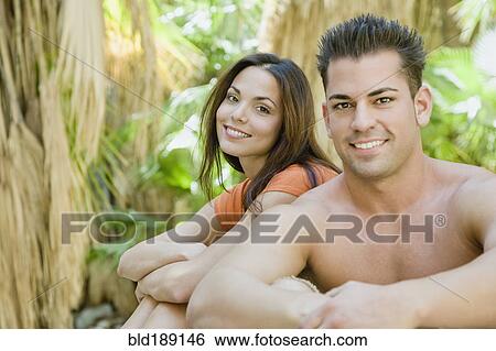 Stock Photograph - Hispanic couple relaxing in tropical area. Fotosearch