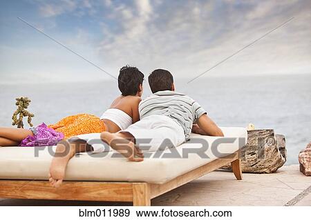Stock Photo - Hispanic couple relaxing near ocean. Fotosearch