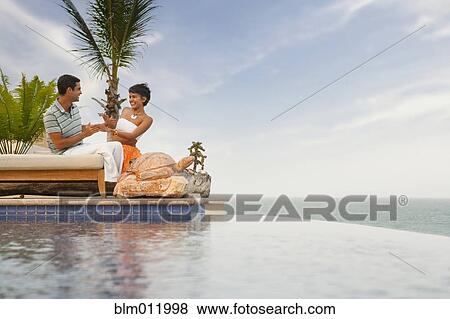 Hispanic couple relaxing near swimming pool View Large Photo Image Stock Photo - Hispanic couple relaxing near swimming pool. Fotosearch