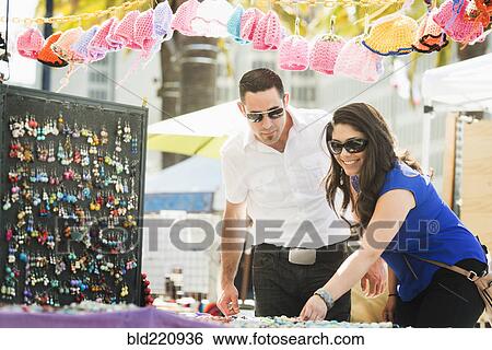 Stock Photograph - Hispanic couple shopping in outdoor market. Fotosearch