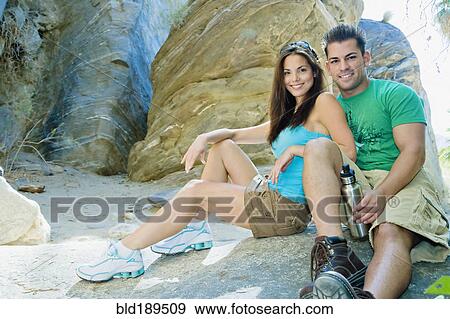 Stock Photo - Hispanic couple sitting near rock. Fotosearch