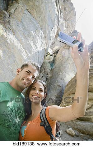 Stock Photo - Hispanic couple taking photographs with cell phone. Fotosearch