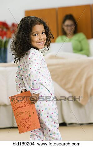 Picture - Hispanic girl with birthday card for mother. Fotosearch