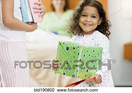 Stock Image - Hispanic girl with birthday gift for mother. Fotosearch