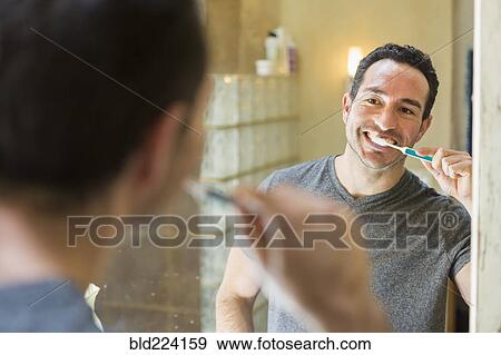 Hispanic man brushing teeth in mirror View Large Photo Image Stock Photo - Hispanic man brushing teeth in mirror. Fotosearch