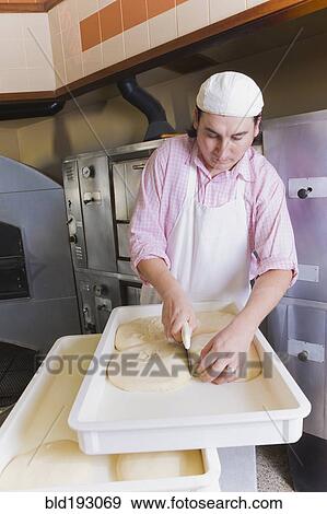 Hispanic man cutting pizza dough View Large Photo Image Stock Photo - Hispanic man cutting pizza dough. Fotosearch