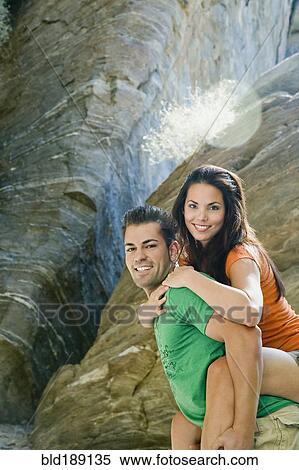 Stock Photography - Hispanic man giving girlfriend piggyback ride. Fotosearch