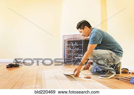 Stock Photo - Hispanic man installing floors in new house. Fotosearch