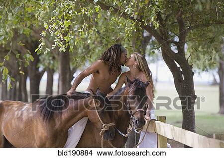 Picture - Hispanic man on horseback kissing girlfriend. Fotosearch