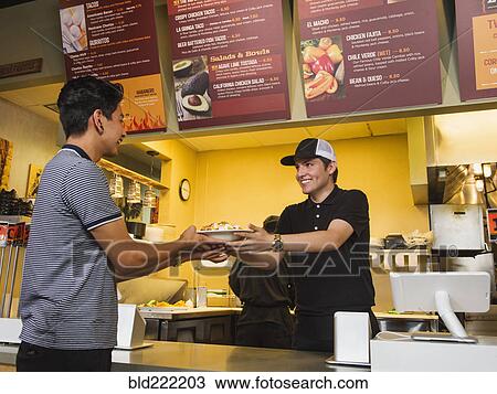 Stock Image - Hispanic man purchasing food in cafe. Fotosearch