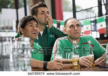 Hispanic men watching television in sports bar View Large Photo Image Picture - Hispanic men watching television in sports bar. Fotosearch