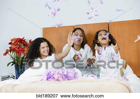 Hispanic mother and daughters throwing feathers in bedroom View Large Photo Image Stock Photo - Hispanic mother and daughters throwing feathers in bedroom. Fotosearch