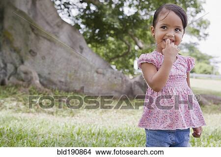 Picture - Hispanic preschool girl standing outdoors. Fotosearch