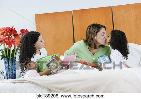 Stock Photograph - Hispanic sisters giving mother birthday gifts. Fotosearch