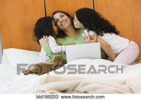 Hispanic sisters kissing mother on bed in bedroom View Large Photo Image Stock Image - Hispanic sisters kissing mother on bed in bedroom. Fotosearch