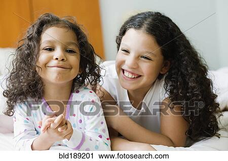 Stock Image - Hispanic sisters laughing. Fotosearch
