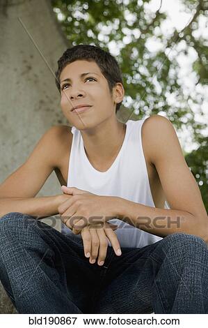 Stock Photo - Hispanic teenage boy sitting outdoors. Fotosearch