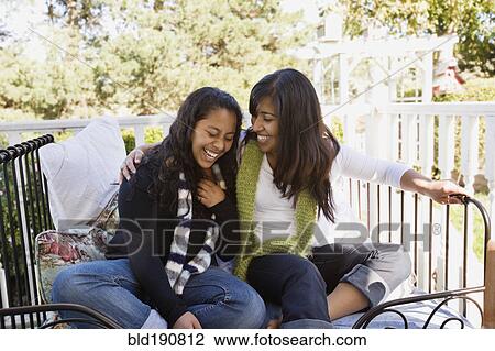 Stock Image - Hispanic teenager and woman laughing on porch. Fotosearch