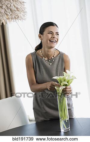 Stock Photo - Hispanic woman arranging calla lilies in vase. Fotosearch