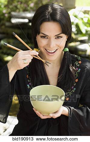 Hispanic woman eating from bowl with chopsticks View Large Photo Image Stock Image - Hispanic woman eating from bowl with chopsticks. Fotosearch