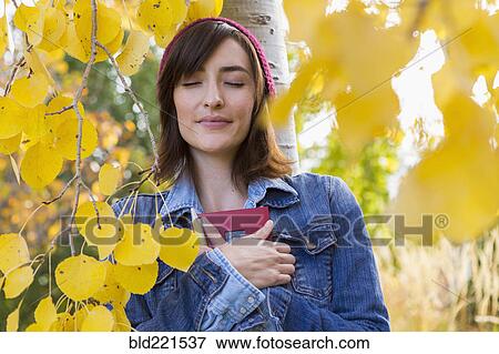 Stock Photo - Hispanic woman holding diary in tree. Fotosearch