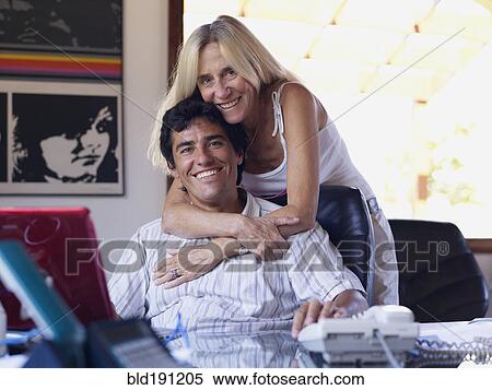 Stock Photography - Hispanic woman hugging son at desk. Fotosearch