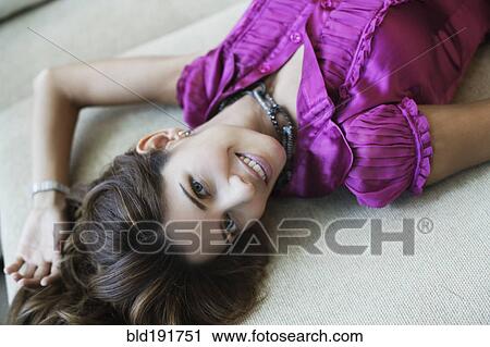 Stock Image - Hispanic woman laying on sofa. Fotosearch