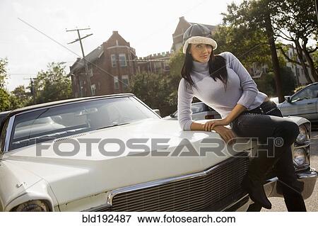 Hispanic woman leaning on hood of car View Large Photo Image Stock Photo - Hispanic woman leaning on hood of car. Fotosearch