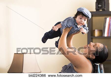 Stock Photograph - Hispanic woman lifting baby son. Fotosearch